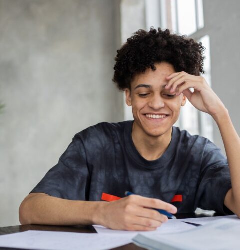 A GCSE student smiling while working through notes