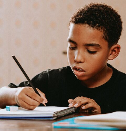 A secondary pupil writing in an exercise book at home