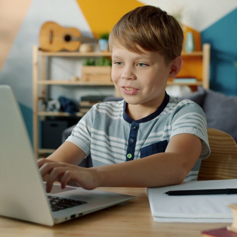 A boy working at a laptop at home