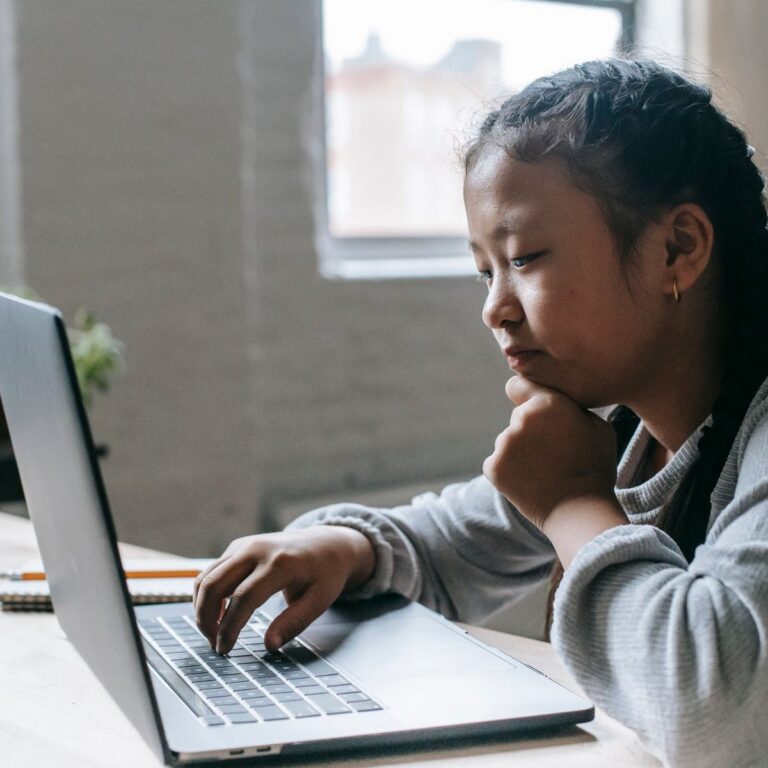 A girl working at a laptop at home